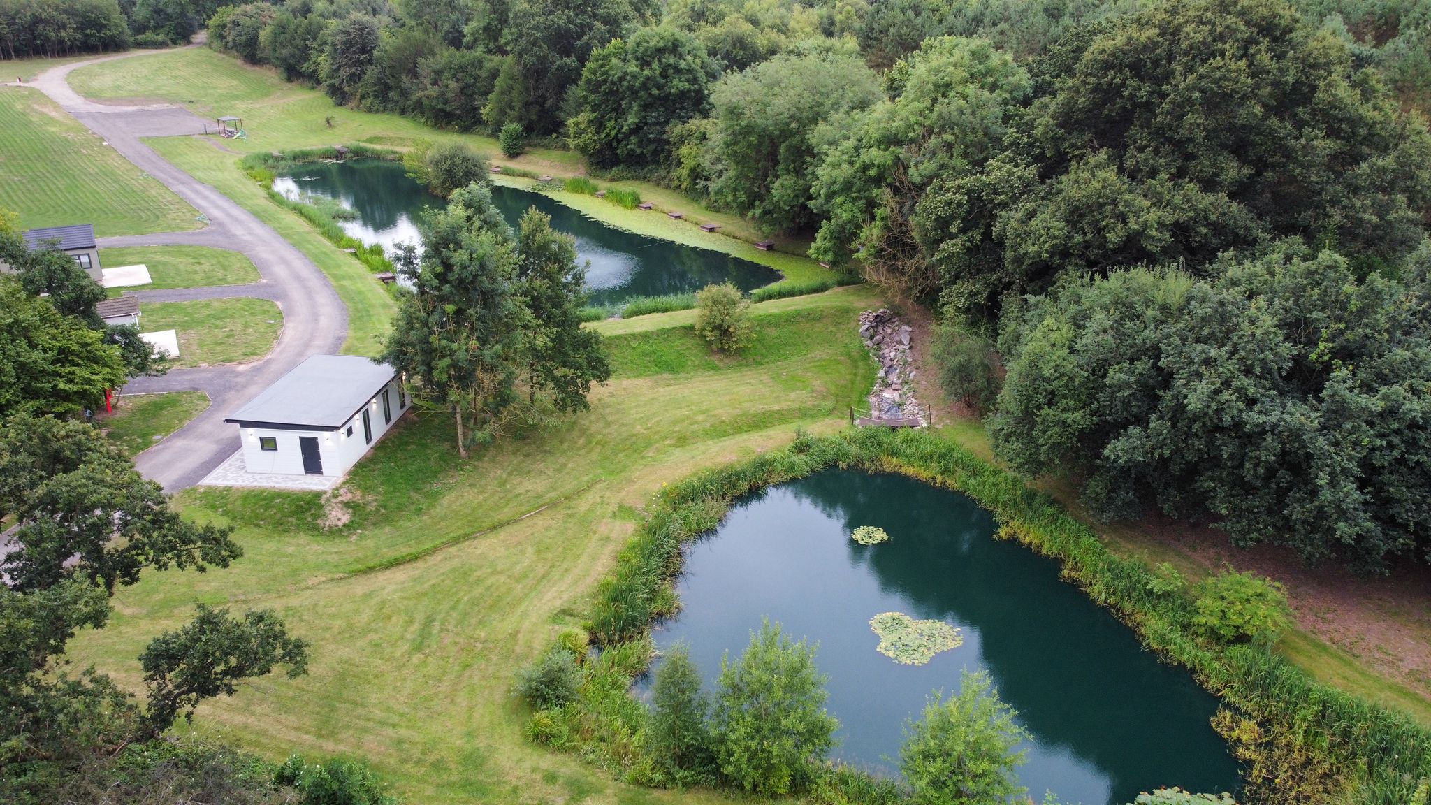 Calm carp fishing lake fringed with trees at Swanlake Lodges, Swannington